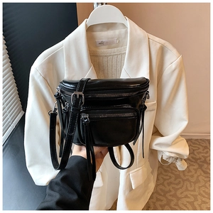 Détail du sac seau en cuir noir brillant montrant plusieurs fermetures éclair de poche