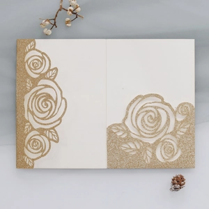 Detail view of laser-cut gold glitter rose pattern on wedding invitation card
