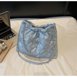 Vue détaillée du sac seau bleu ciel matelassé avec rivets argentés et étoile en strass