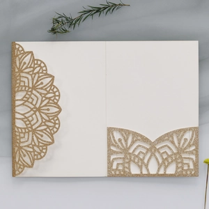 Detailed laser-cut ivory wedding invitation with gold glitter and floral patterns
