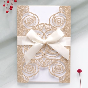 Close-up of glitter champagne gold rose laser-cut wedding card with ivory satin bow