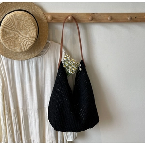 Detail of black hollow knit tote bag featuring leather straps and woven mesh texture