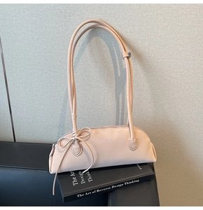 Detail of pink leather handbag with a bow decoration placed on a black book