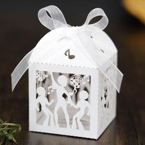 Macro detail of laser-cut dancing figures and musical notes on white favor box