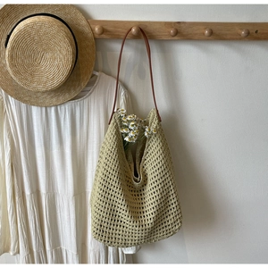 Close-up of light green crochet knit tote bag texture with brown leather shoulder strap