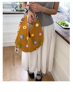 Detail of hollow knit tote bag with 3D floral accents and wide colorful shoulder strap