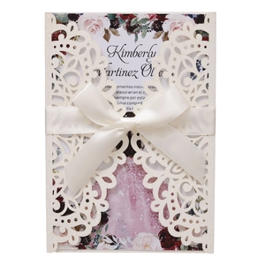 Detailed laser-cut wedding invitation with white ribbon and floral inner card