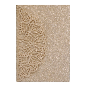 Macro detail of gold glitter wedding invitation featuring intricate laser-cut mandala floral patterns