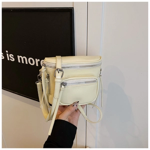 Détail du sac seau en cuir PU crème avec fermetures éclair argentées et coutures nettes