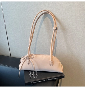 Detail of light pink shoulder bag with decorative bow and sleek minimalist texture