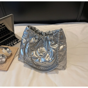 Détail du sac seau argenté matelassé avec logo étoile et bandoulière chaîne