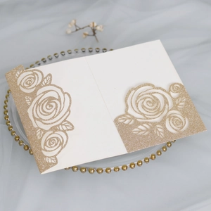 Macro shot of laser-cut champagne gold glitter rose invitation card with floral details