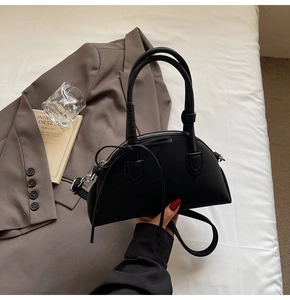 Detail of black pebbled leather underarm bag featuring a delicate bow and silver zipper