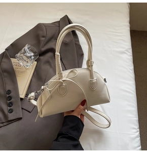 Detailed view of a white shell handbag with a bow detail and detachable shoulder strap