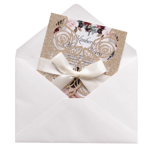 Detail of laser-cut glitter rose invitation with white envelope and satin ribbon bow