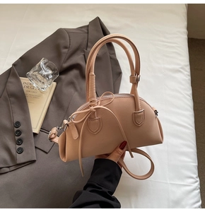 Detail of pink PU leather bag featuring woven handle and delicate bow accent