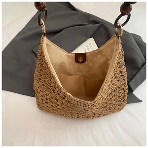 Detail view of woven straw tote bag with brown wood bead handle and inner lining