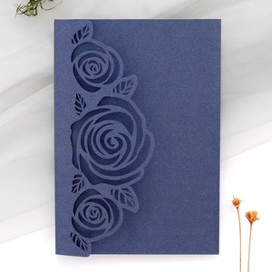 Detailed laser-cut rose patterns on dark blue cardstock wedding invitation cover