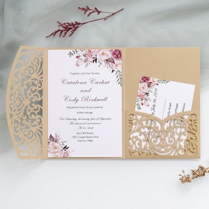 Close-up of laser-cut gold lace pocket wedding invitation with floral insert and card