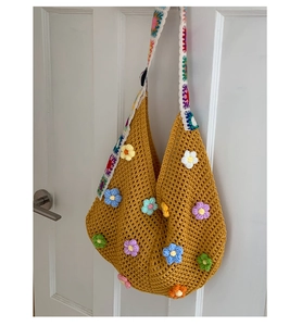 Detail of a large yellow crochet hobo bag with 3D floral accents and colorful straps
