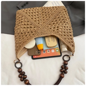 Detail of hollow-woven straw tote with large capacity and bohemian wooden bead handle