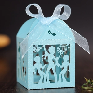 Macro shot of light blue laser-cut party favors box featuring disco dancers and music notes
