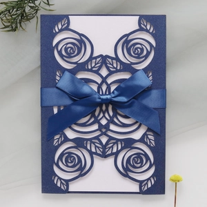 Detail of laser-cut rose patterns on dark blue card with elegant ribbon and white inner card