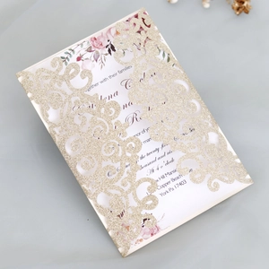Detailed close-up of laser-cut glitter wedding invitation with floral insert and gold texture