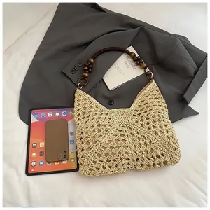 Detail of hand-woven beige straw tote bag featuring decorative dark brown wooden beads