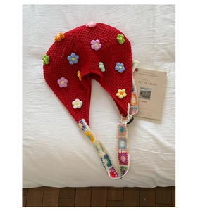 Detail of red crochet bucket hat with colorful flower appliques and knitted straps