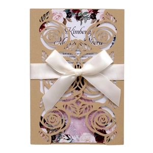Detail of laser-cut rose invitation card with a white satin ribbon bow and floral insert