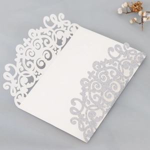 Detail of silver glitter laser cut wedding invitation with elegant hollow floral pattern