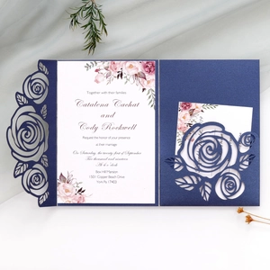 Detail of laser-cut navy blue wedding invitation with intricate rose floral patterns