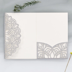 Macro shot of silver glitter wedding invitation featuring intricate laser-cut floral details