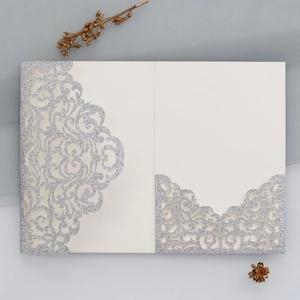 Detail der lasergeschnittenen creme-weißen Hochzeitseinladung mit silbernem Glitzer