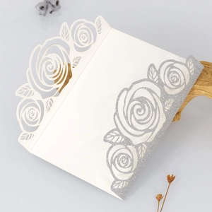 Detailed laser-cut rose floral pattern on off-white wedding card with silver glitter
