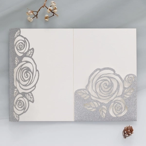 Detailed laser-cut white wedding invitation with silver glitter rose floral patterns