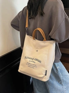 Large beige canvas tote bag with brown straps shown on a model for casual daily style