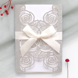 Detail of silver glitter wedding invitation featuring laser-cut rose and satin bow