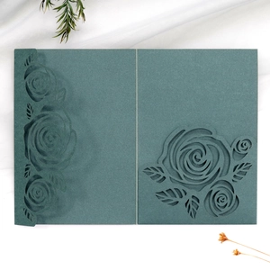 Detail view of laser-cut dark green card with elegant rose patterns and matte texture