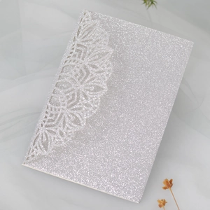 Detail of silver glitter wedding invitation with laser-cut lace edge on white tulle