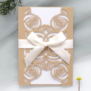 Detail of laser-cut rose invitation with white card and beige satin ribbon bow