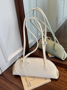 Chic cream bow shoulder bag for women on vintage books in an elegant mirrored room