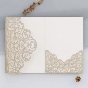 Detail der lasergeschnittenen champagnergoldenen Glitzereinladung mit elegantem Rollmuster