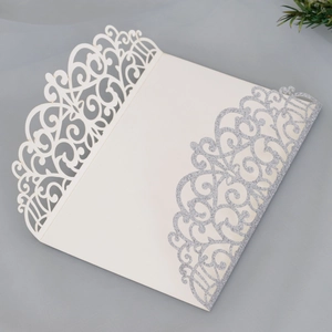 Detail of laser-cut floral invitation cover with silver glitter finish on cream cardstock