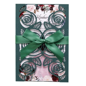 Detail of dark green laser-cut floral invitation with satin bow and pink floral insert