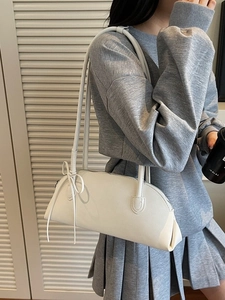 Minimalist white leather baguette bag with side bow detail for women in a casual outfit