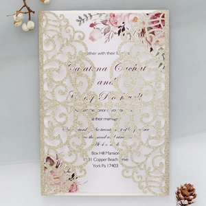 Close-up of gold glitter laser-cut invitation with floral inner card and scroll patterns