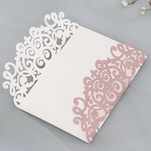 Detail of laser-cut wedding invitation sleeve with pink glitter and elegant scroll patterns