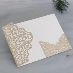 Detailliertes lasergeschnittenes Goldglitzermuster auf eleganter weißer Hochzeitseinladung